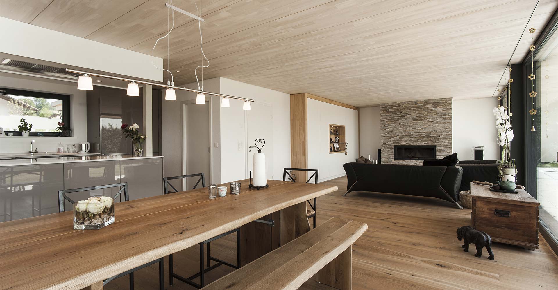 Wohn- und Esszimmer aus Holz mit schwarzen Sitzmöbeln